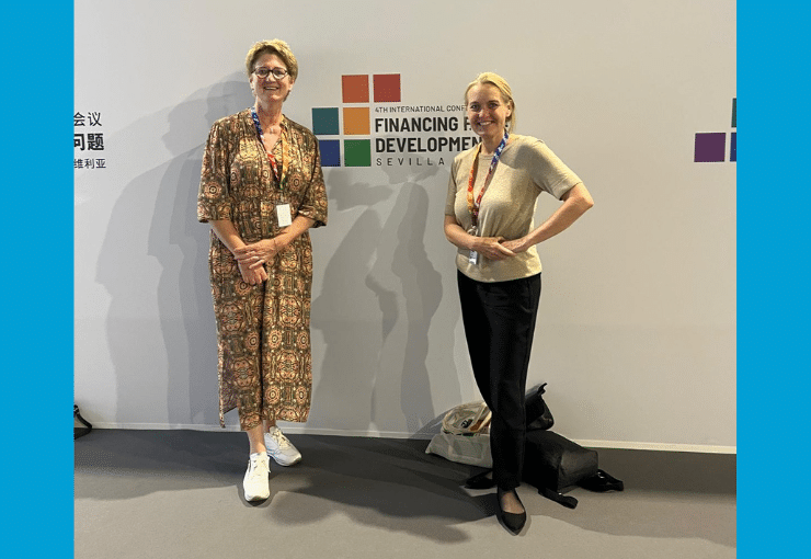 Picture of Mariëlle Bemelmans and Barbara Feinig in front of a wall with the logo of the 4th Financing for Development Conference on it.
